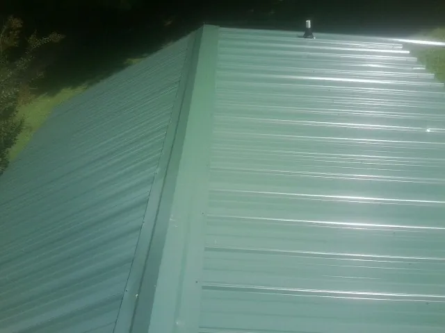 New green metal panels meeting at the ridge of a roof — Flat Roof Repair work by our crew in Pendleton